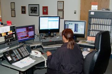 A dispatcher works at a desk and views information on a computer